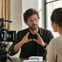 Freelance producer guiding a client video shoot in an airy location studio