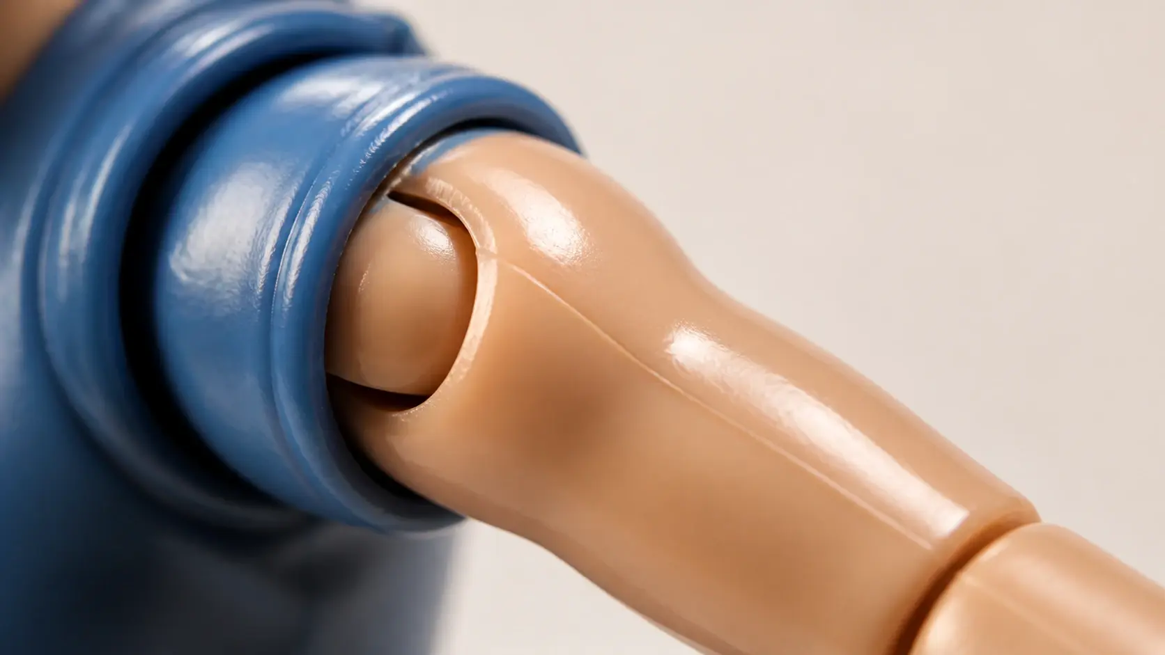 Macro of a collector figure's shoulder showing glossy moulded plastic, a parting seam and a ball joint