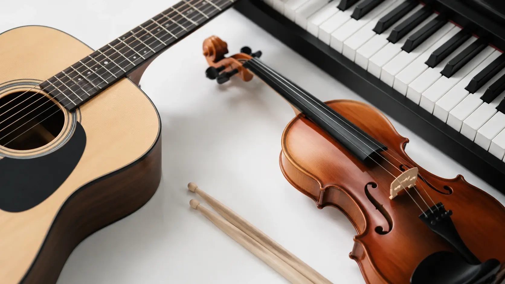 Guitar, piano, violin, and drumsticks arranged on white surface
