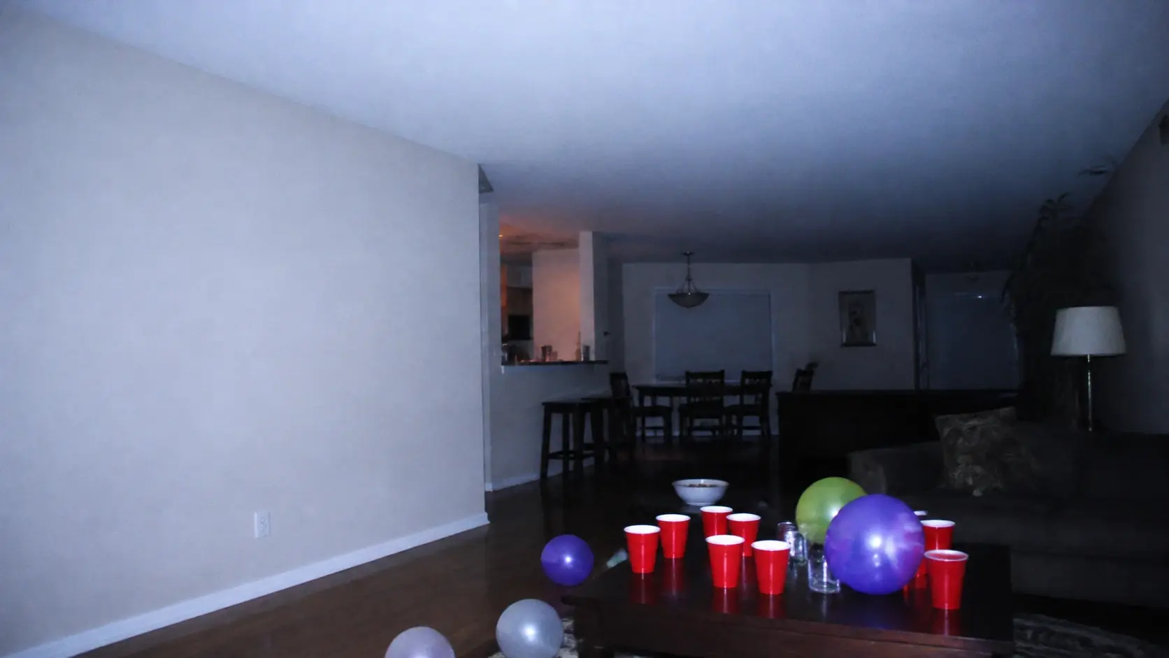 A wide living room party lit by one harsh camera flash with washed highlights and cool colour