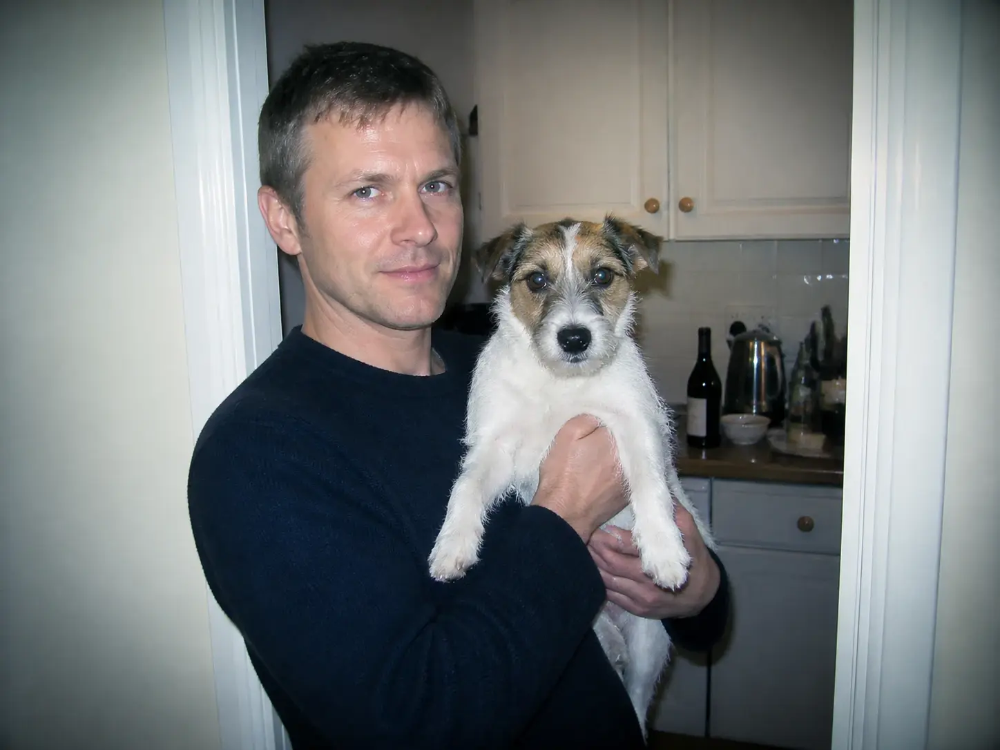 A man holding a terrier in a doorway, pose and framing unchanged under the 2000s rendering