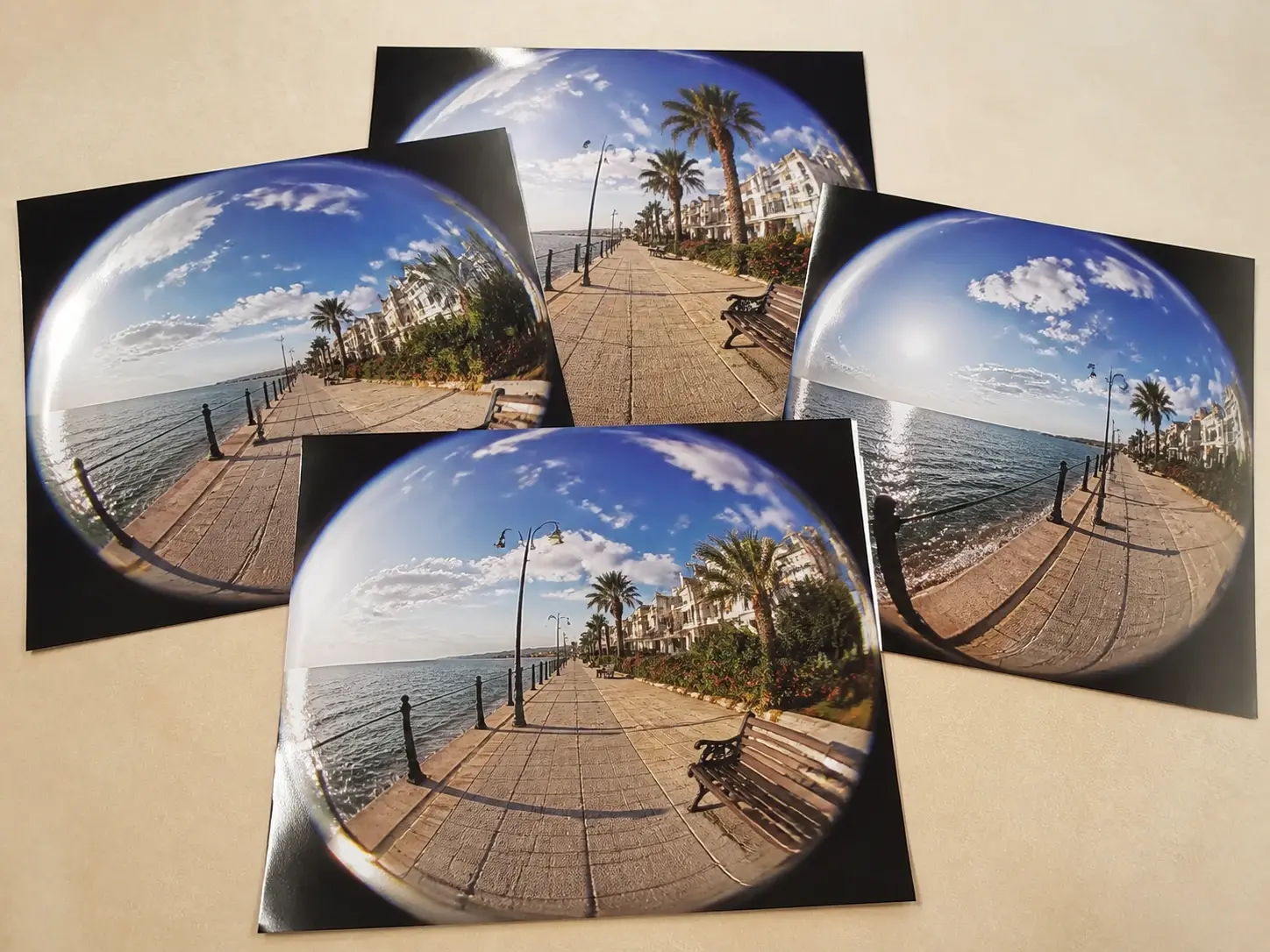 Four large prints of the same fisheye promenade view overlapping on a studio table, none carrying a watermark