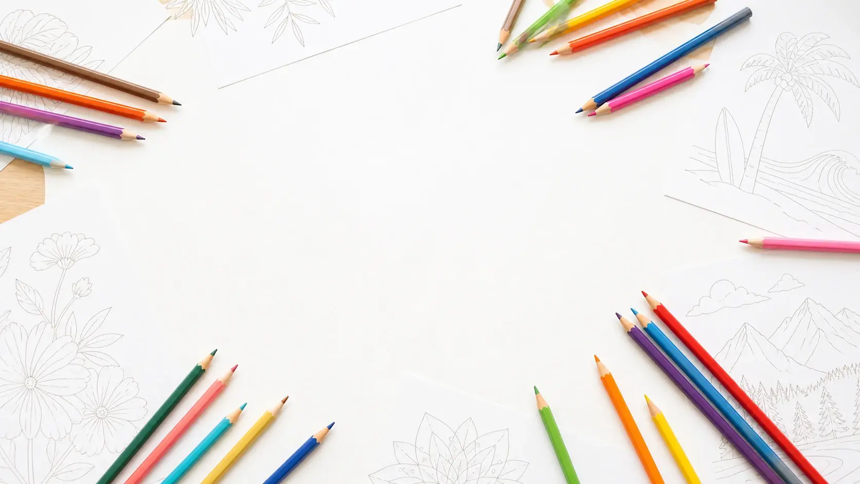 A wide bright table spread with printed outline sheets and a scatter of coloured pencils